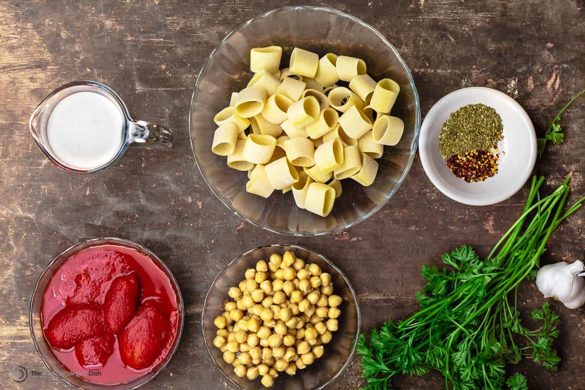 ingredients for pasta with chickpeas including pasta, heavy cream, tomatoes, chickpeas, parsley, and spices