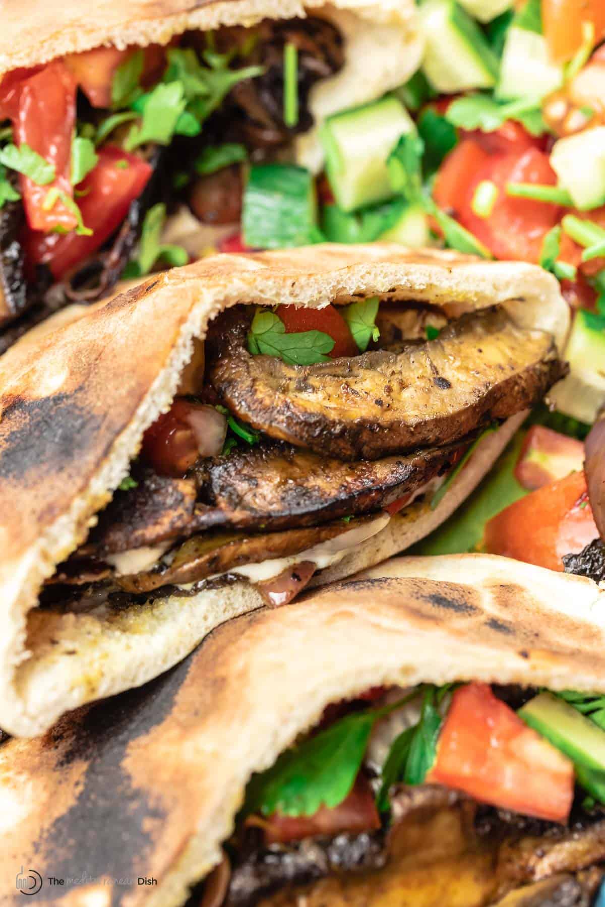 mushroom shawarma in pita bread served with Mediterranean tomato and cucumber salad