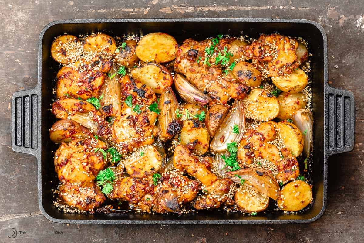 baharat thighs with potatoes and shallots in a cast-iron baking pan