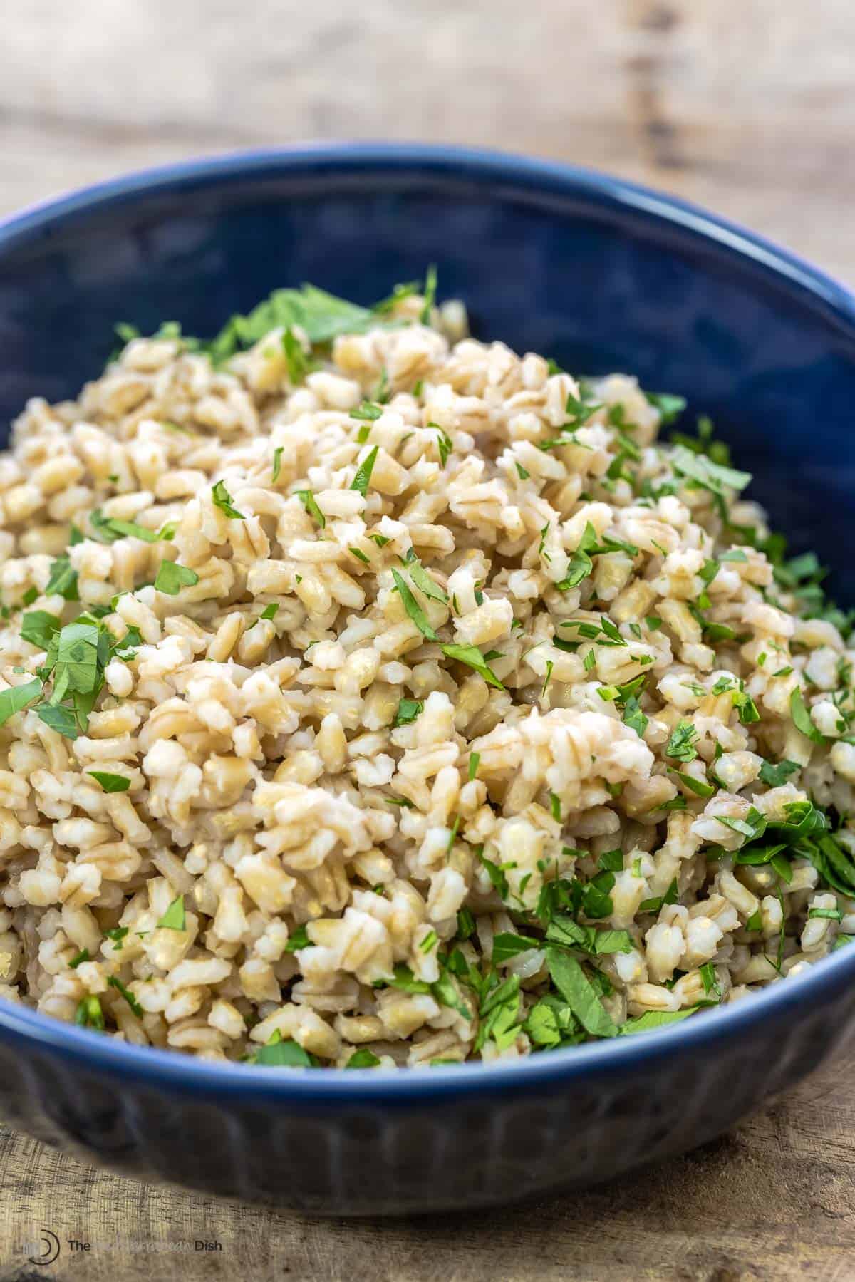 Side angle shot of cooked barley in a blue bowl 