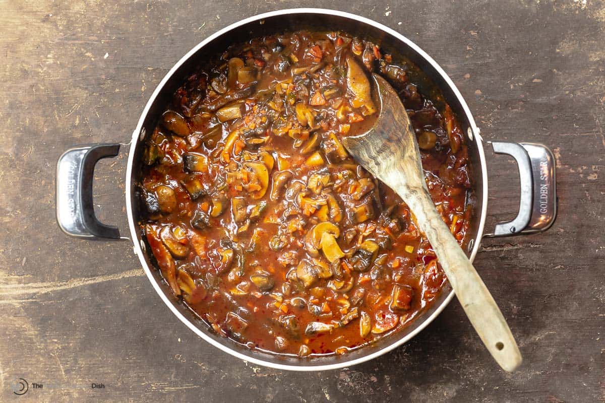 mushroom ragu in a pot with a wooden spoon