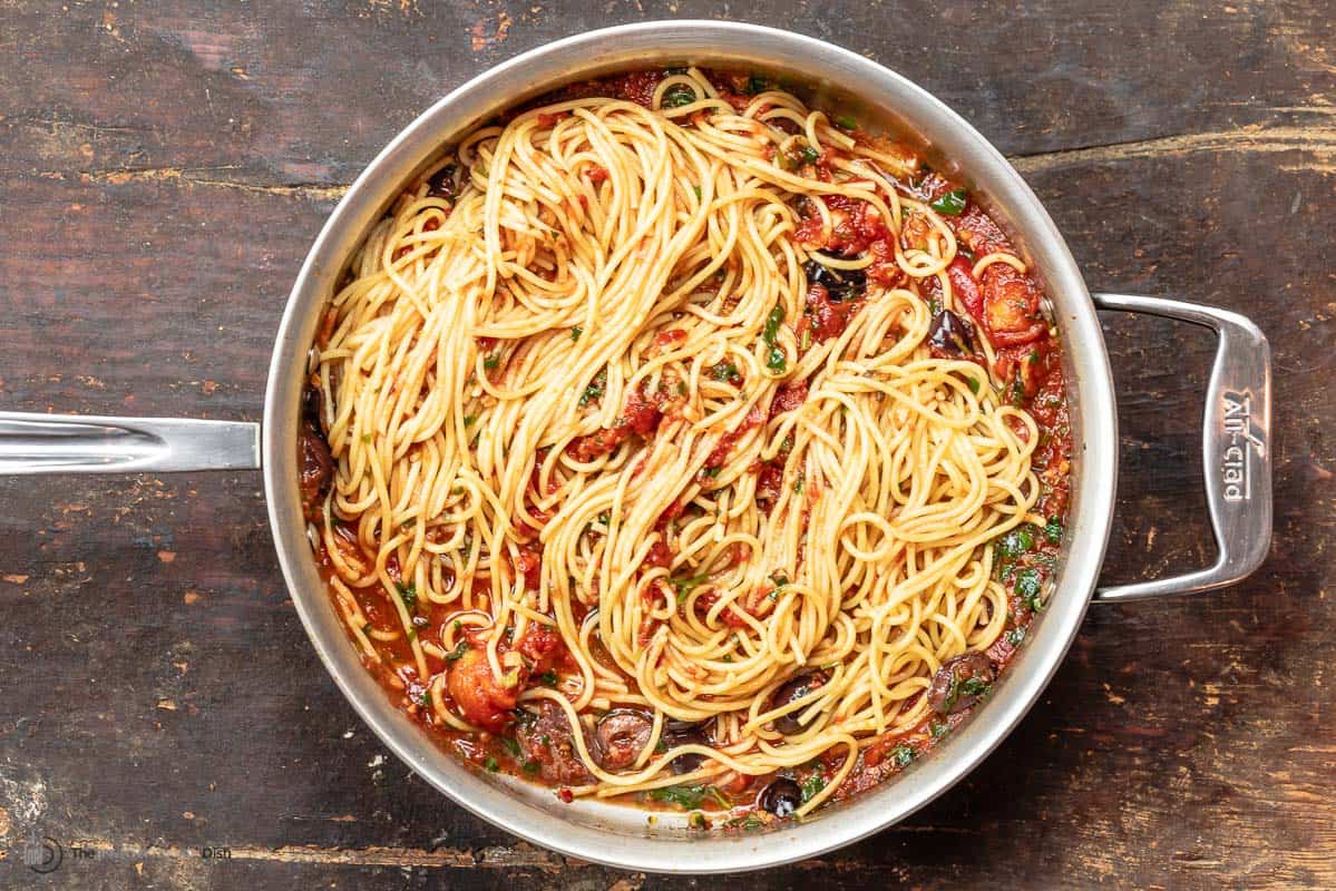 spaghetti puttanesca in a saucepan