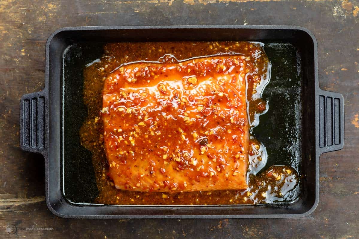 salmon coated with spicy harissa sauce and placed in a cast iron baking dish
