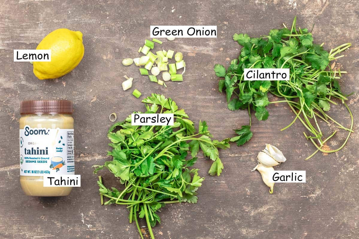 labeled ingredients for vegan green goddess dressing including lemon, green onion, cilantro, garlic, parsley, and sesame tahini