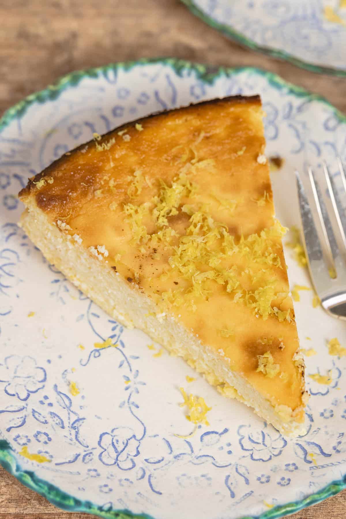 slice of lemon ricotta cheesecake on a small plate with a sprinkle of lemon zest