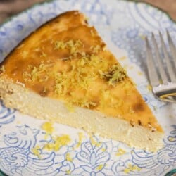 slice of Italian cheesecake on a small plate with a sprinkle of lemon zest. Fork on the side