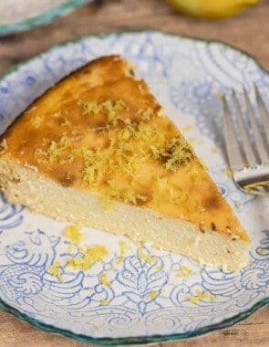 slice of Italian cheesecake on a small plate with a sprinkle of lemon zest. Fork on the side