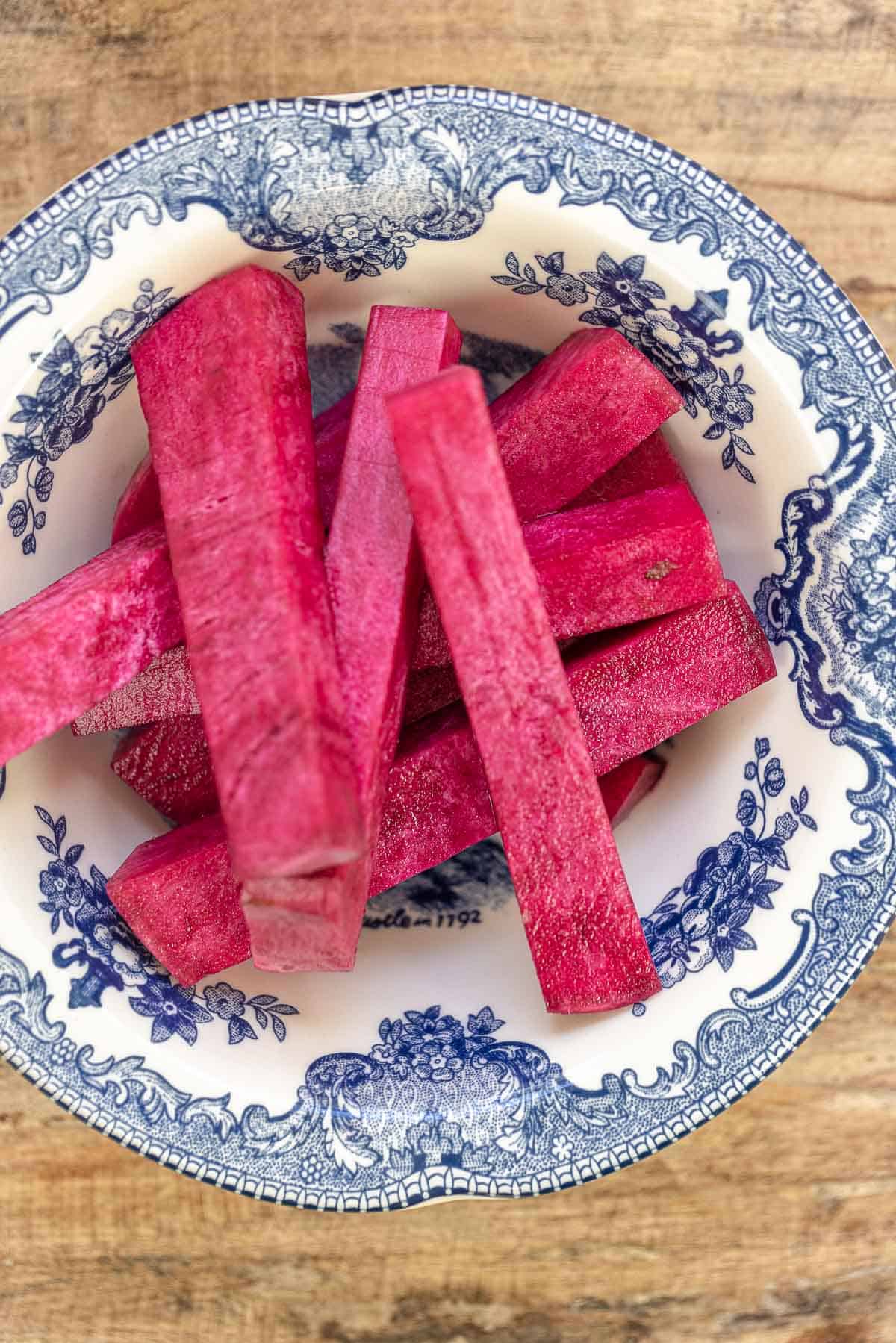 sliced turnip pink pickles in a small blue and white bowl