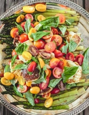 roasted asparagus salad with cherry tomatoes, halloumi cheese, and basil leaves