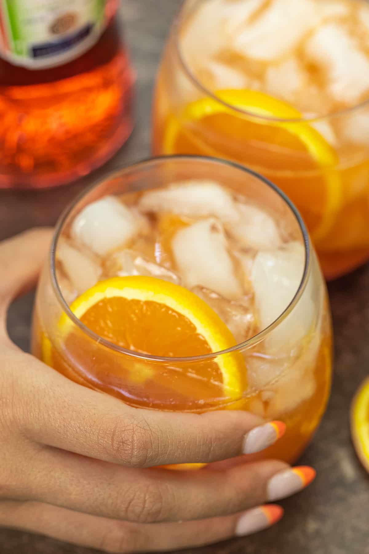 a hand holding an Italian aperol spritz cocktail.