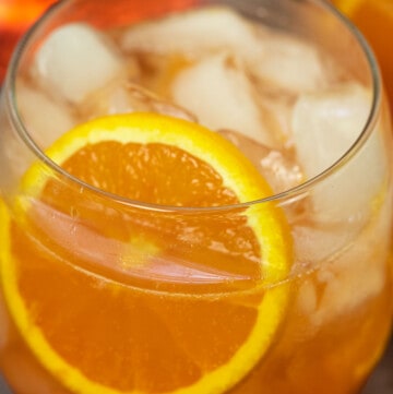 close up of aperol spritz with ice and fresh orange slice.