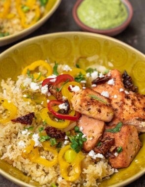 salmon rice bowls with colorful vegetables like bell peppers in a yellow bowl