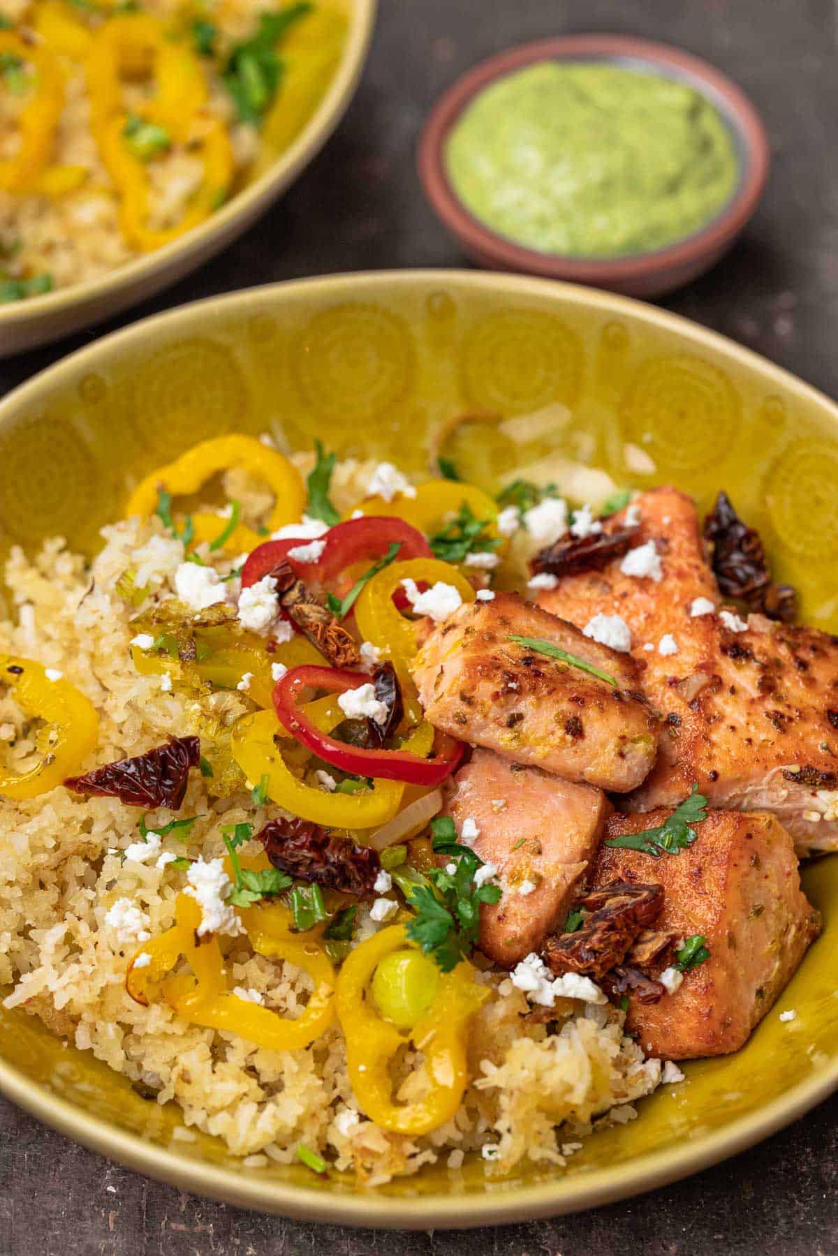 salmon rice bowls with colorful vegetables like bell peppers in a yellow bowl