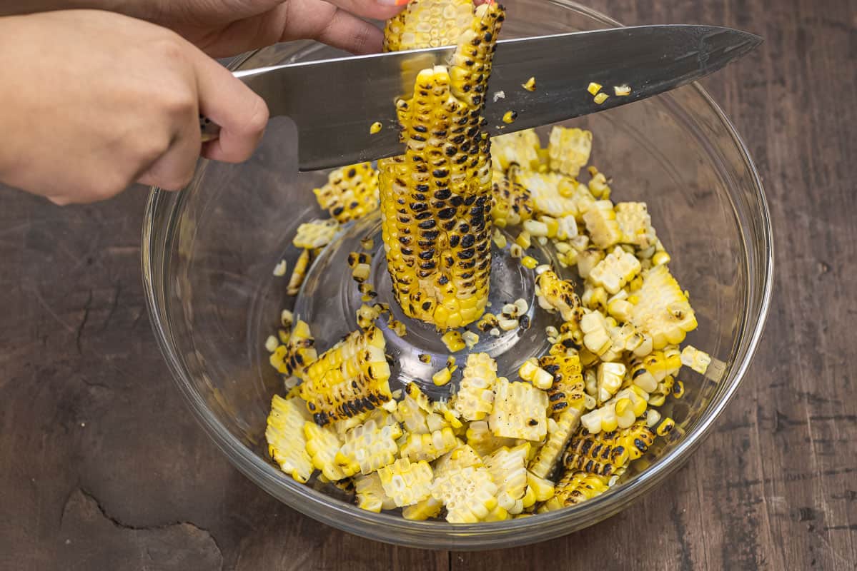 cutting corn kernels off the cob after grilling using a sharp knife.