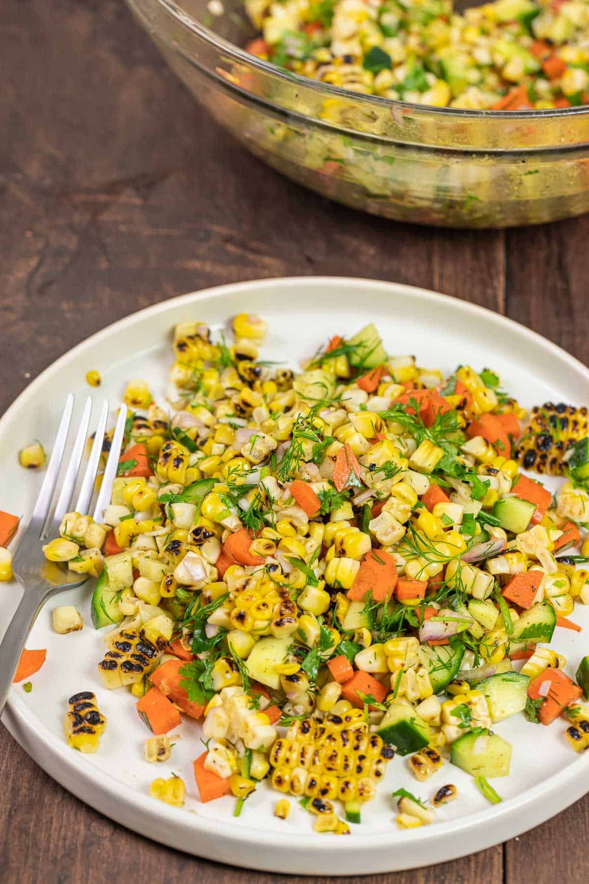 grilled corn salad o a white plate with a fork.