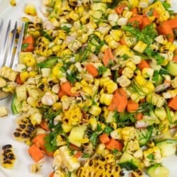 close up of summer corn salad with fresh vegetables and herbs on a plate.