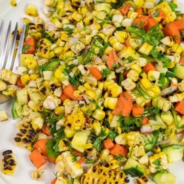 close up of summer corn salad with fresh vegetables and herbs on a plate.