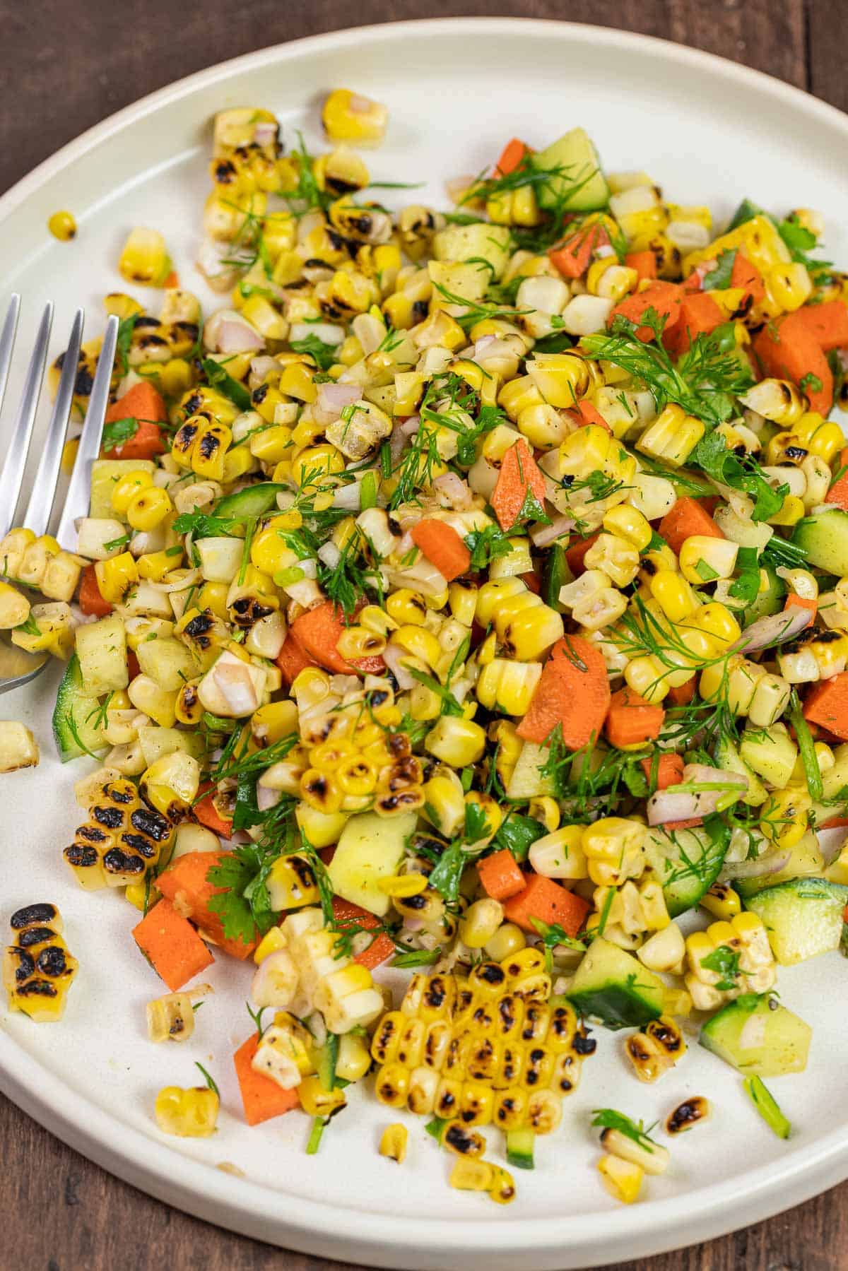 close up of summer corn salad with fresh vegetables and herbs on a plate.