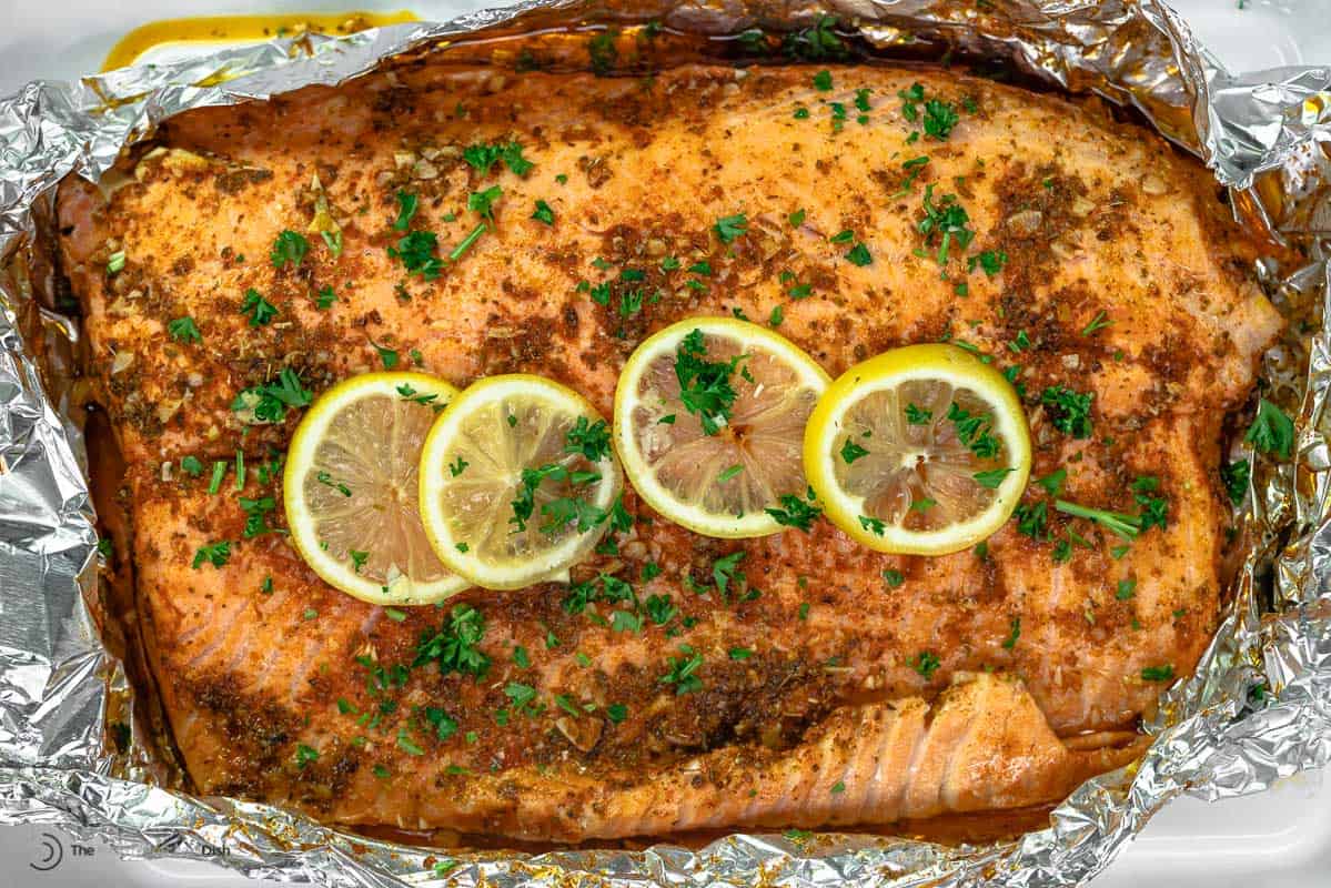 grilled salmon in foil topped with lemon slices and fresh parsley.