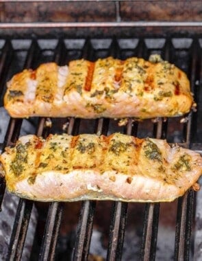 2 pieces of grilled salmon on the grill with the charred flesh side facing up.