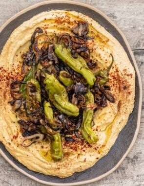 loaded hummus topped with shallots, shishito peppers, and a sprinkle of sumac and Aleppo-style pepper