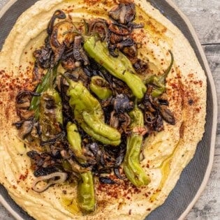 loaded hummus topped with shallots, shishito peppers, and a sprinkle of sumac and Aleppo-style pepper