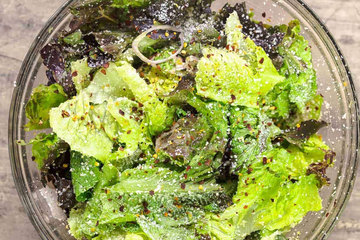 Lettuce, Parmesan cheese, shallots, olive oil, and crushed red pepper in a mixing bowl