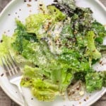 lemon parmesan lettuce salad on a white plate with a fork.