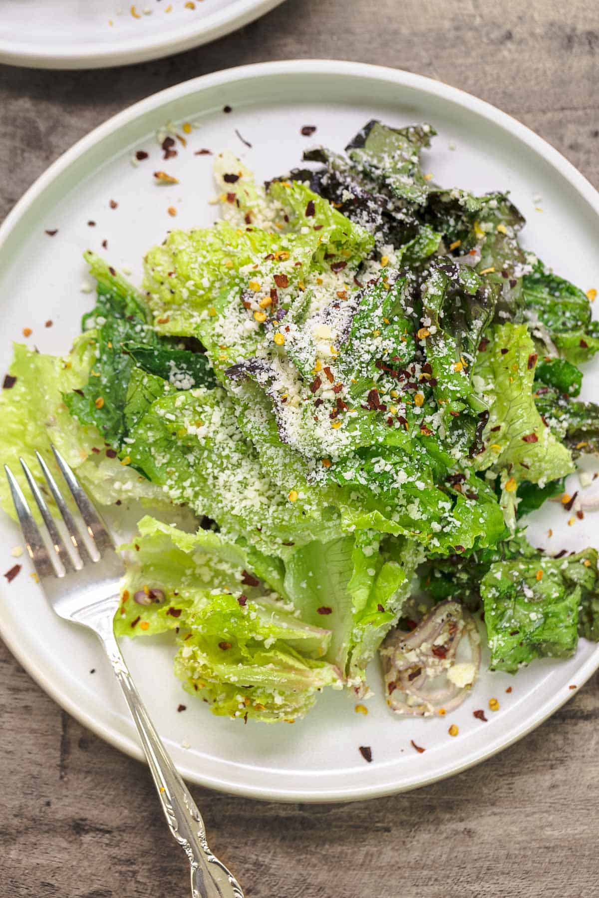 Lemon parmesan lettuce salad on a white plate with a fork.