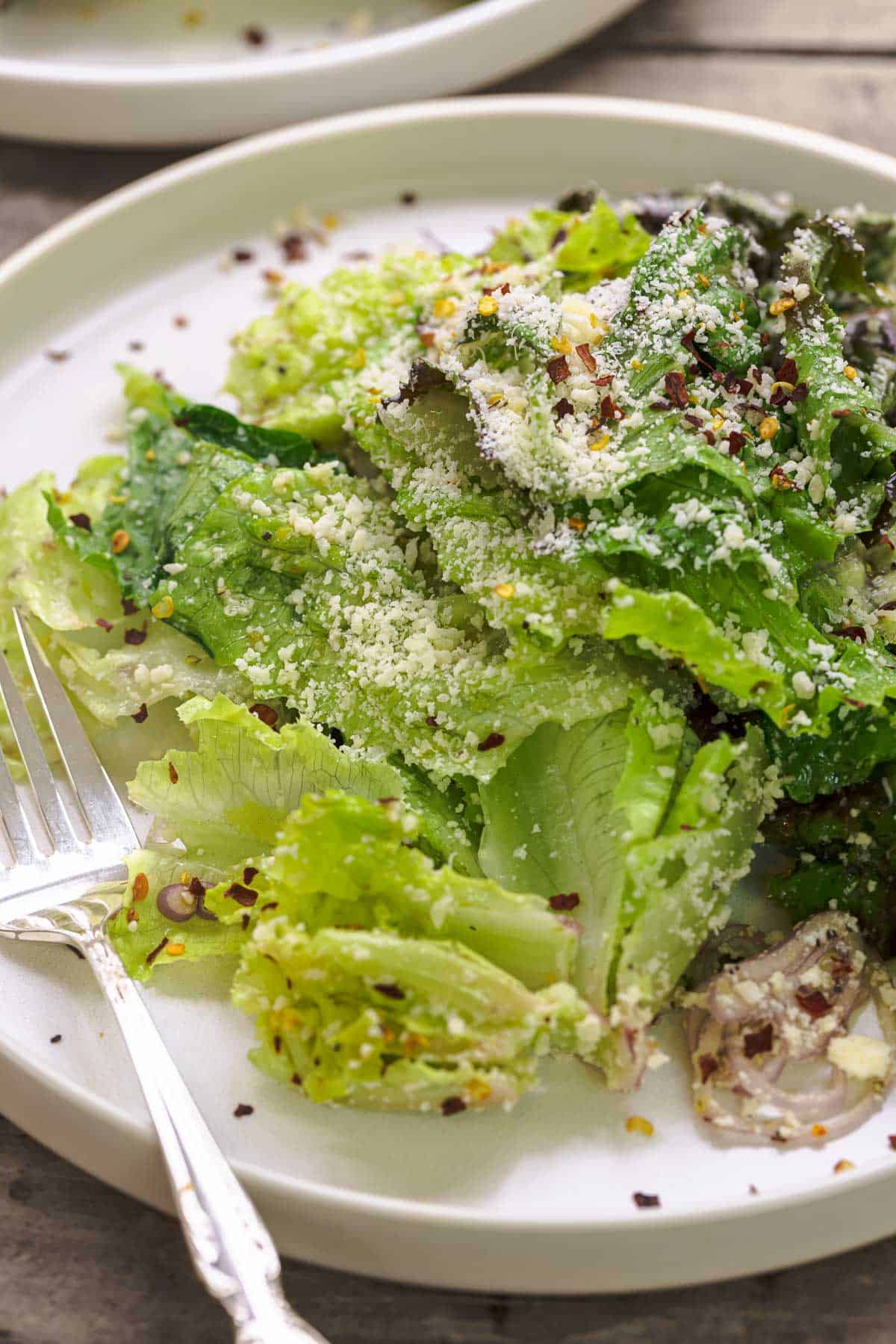salad with lettuce, parmesan, lemon zest, shallots, and red pepper flakes on a plate.