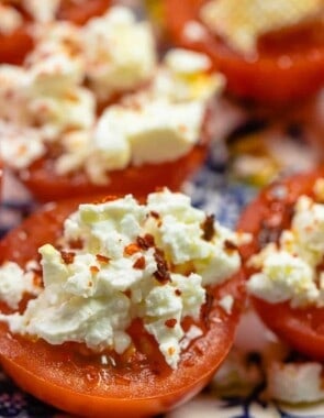 close up photo of sliced fresh tomato with crumbled feta and red pepper flakes