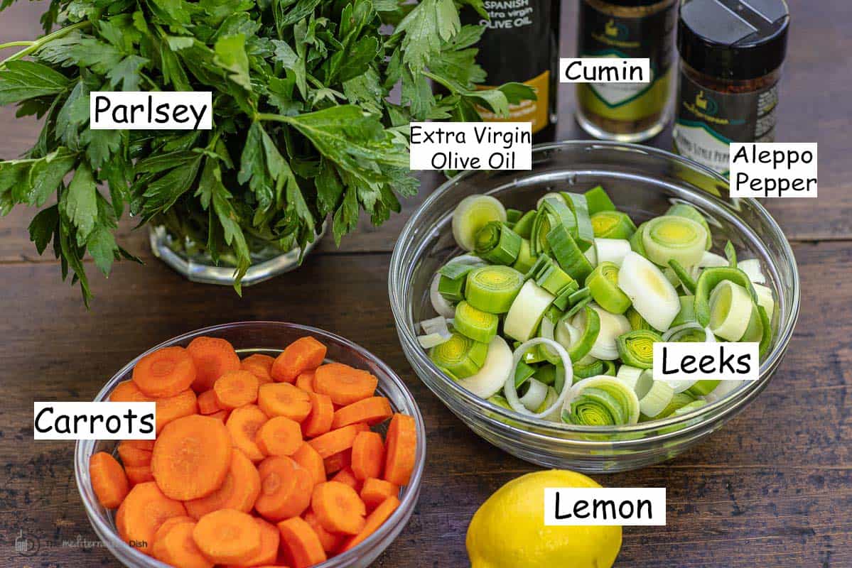labeled ingredients for leeks including flat-leaf parsley, carrots, leeks, lemon, extra virgin olive oil, cumin, and aleppo pepper.
