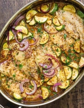recipe for flounder including baked flounder fillets and vegetables in a baking dish.