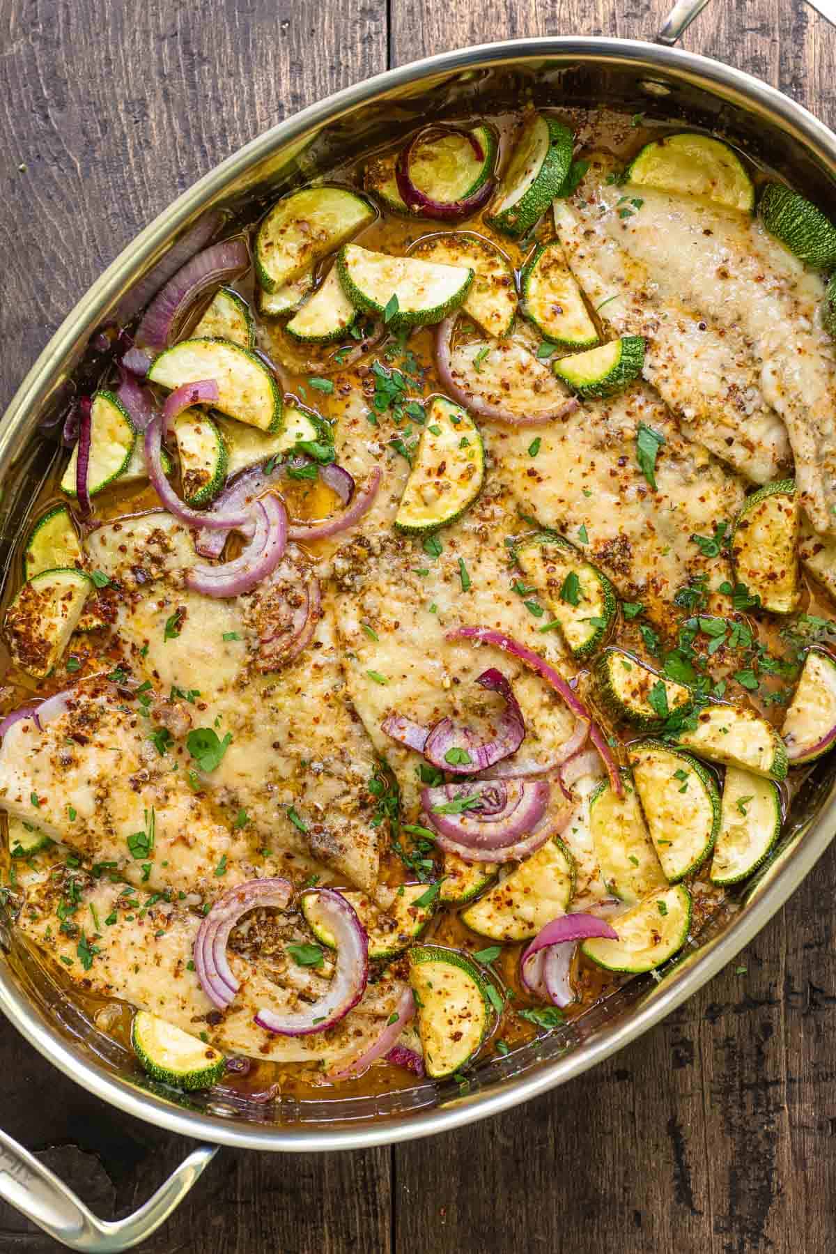 recipe for flounder including baked flounder fillets and vegetables in a baking dish.