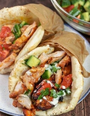chicken doner kebab wrapped in a pita with tomato and cucumber salad and drizzled with sauce.