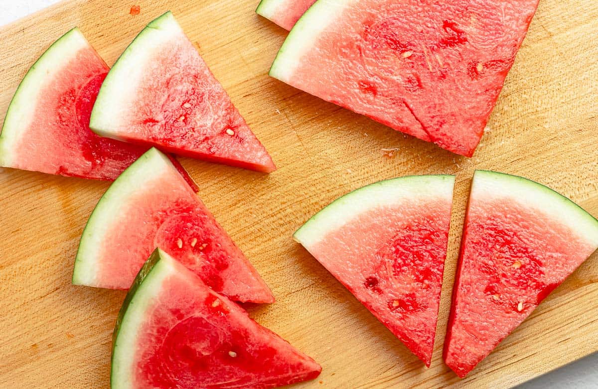 close up of watermelon wedges on a cutting board.
