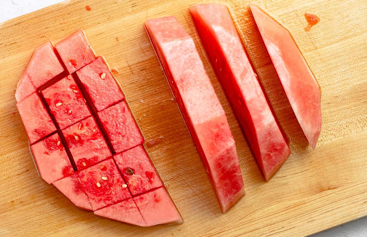 step image for how to cut a watermelon into cubes: a skinless watermelon cut into cubes on a cutting board.
