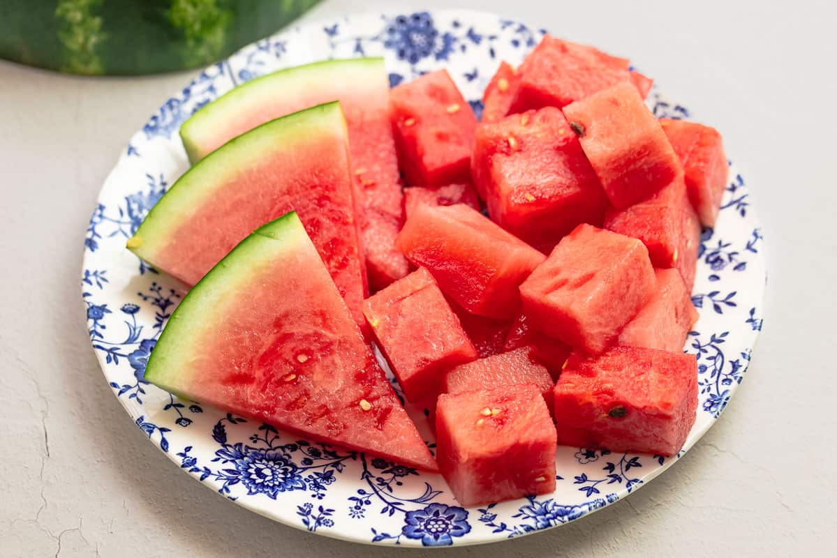 watermelon wedges and cubes on a blue and white plate.