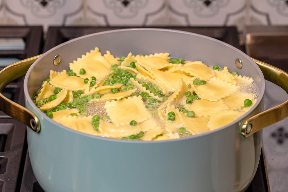 ravioli and peas boiling in a large pot of water.