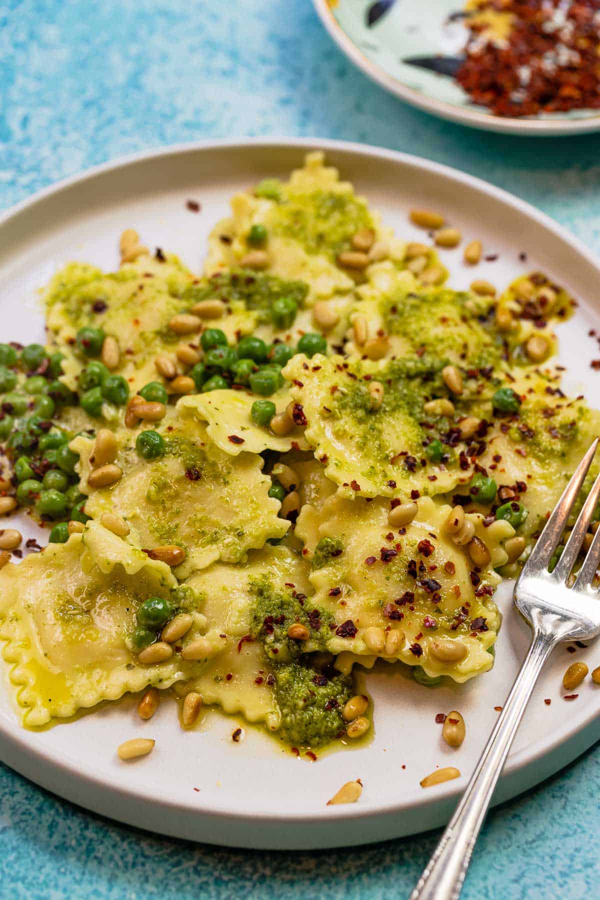 close up of ravioli recipe with pesto, toasted pine nuts, and Aleppo pepper.