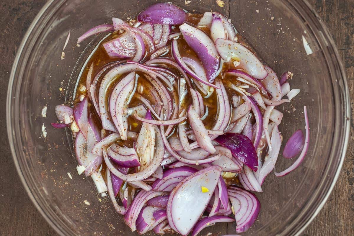 sliced red onion and minced garlic in a bowl with red wine vinegar and lemon juice.