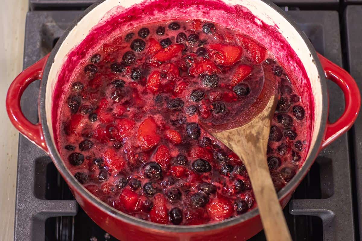 fruit compote cooking on the stove in a large pot.