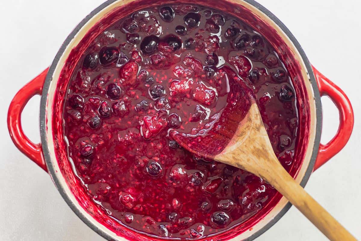 completed triple berry compote in a red pot.