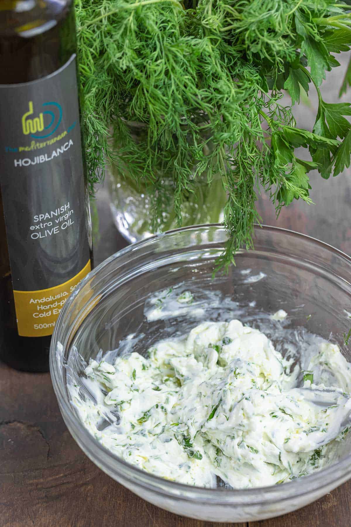 herbed labneh dip in a bowl next to olive oil and fresh dill.