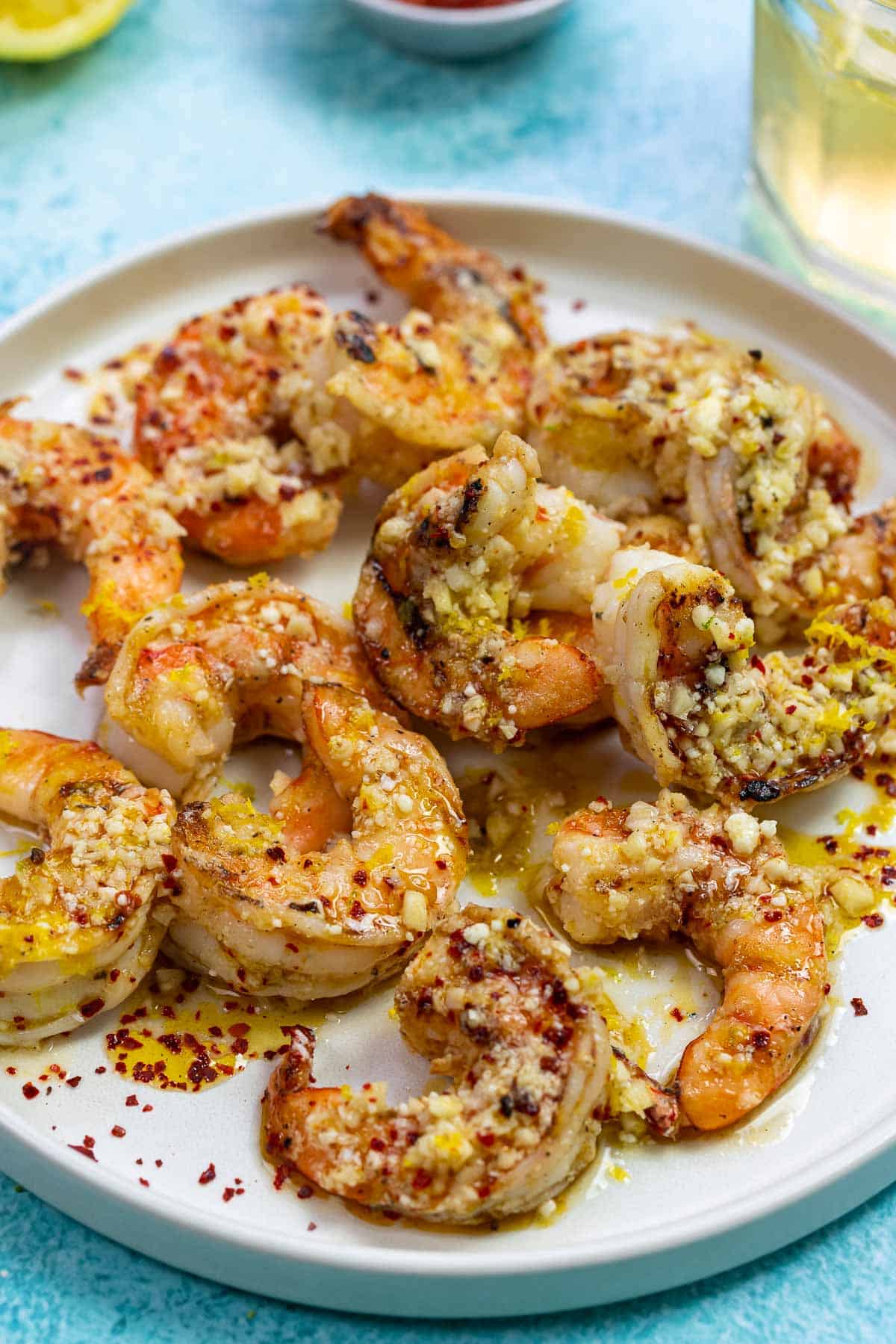 garlic parmesan shrimp on a white plate with some red pepper flakes sprinkled over.