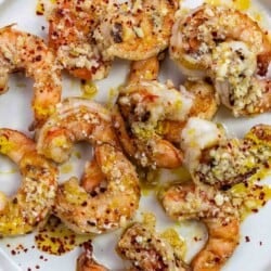 cooked shrimp on a plate with lemon-garlic sauce and parmesan cheese.