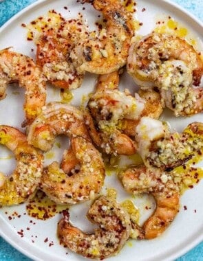 cooked shrimp on a plate with lemon-garlic sauce and parmesan cheese.