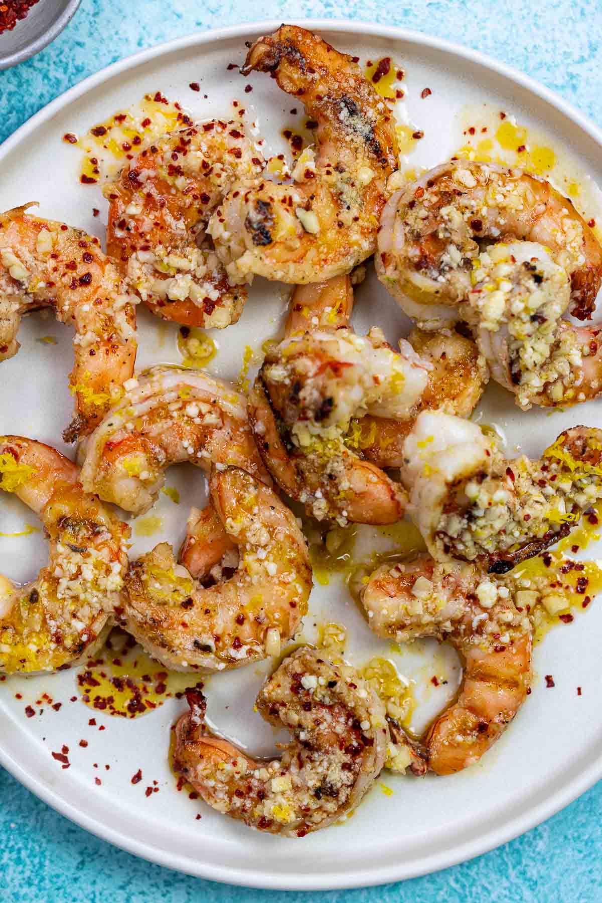 cooked shrimp on a plate with lemon-garlic sauce and parmesan cheese.