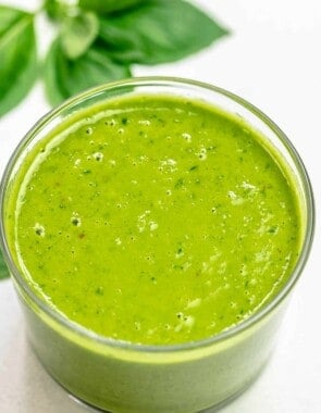 basil vinaigrette in a small jar with basil leaves in the background.