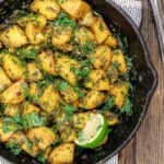 Batata harra with a lime wedge for garnish in a skillet.